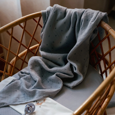 Manta cinzenta com padrões pequenos num berço de vime