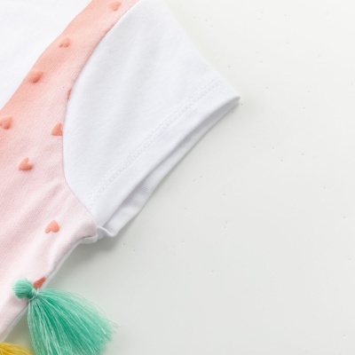 Manga branca com detalhe rosa de corações em relevo e pompons verdes e amarelos