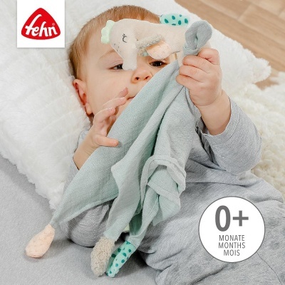 Bebé com brinquedo de pano azul e peluche elefante sentado