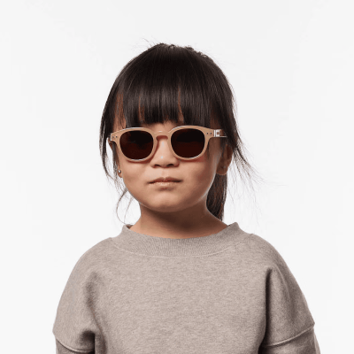 Criança com óculos de sol bege e camisola cinza