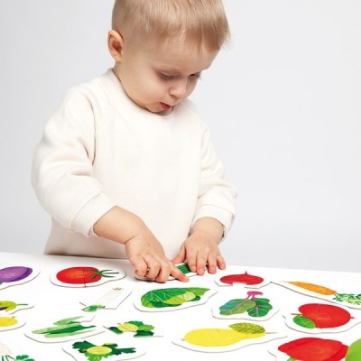 Criança a montar puzzle de frutas e legumes de madeira