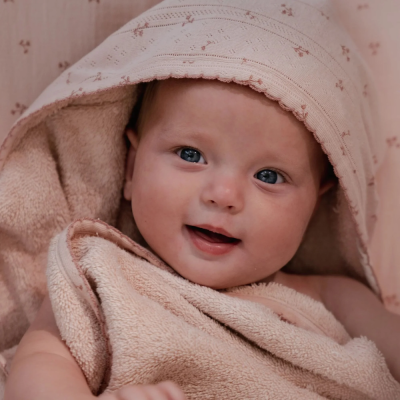 Bebé com toalha de banho rosa com padrão floral