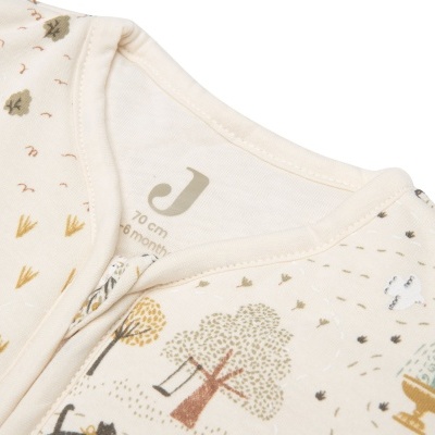 Roupa de bebé creme com padrão de árvores e fontes coloridas.