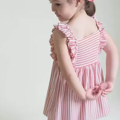 Menina de costas com vestido riscado branco e vermelho e fita cor-de-rosa no cabelo