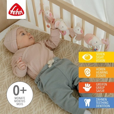 Bebé deitado a brincar com brinquedo de tecido no berço