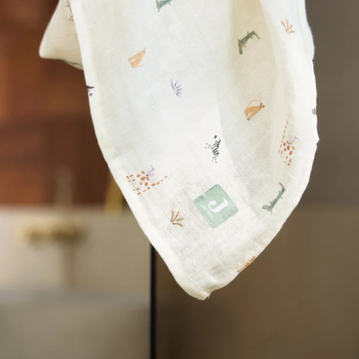 Pano branco com estampados de animais e etiqueta verde com letra J