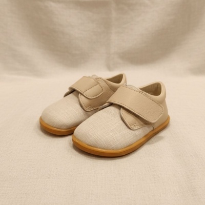 Sapatinhos infantis bege com tira de velcro e sola castanha.