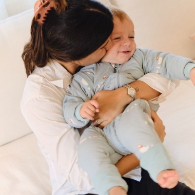 Pessoa abraçando criança com pijama azul claro sentado num sofá branco