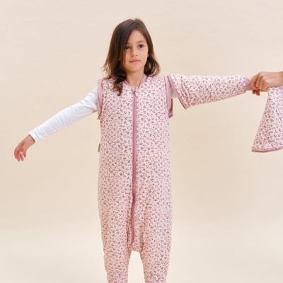 Criança com saco de dormir rosa floral e meia cor-de-rosa