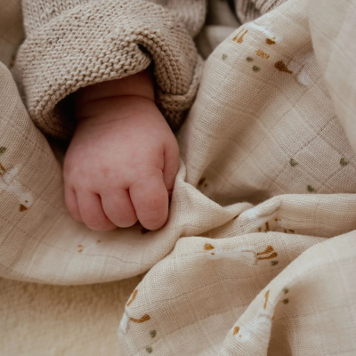 Mão de bebé com camisola tricotada e tecido de algodão com padrão de animais