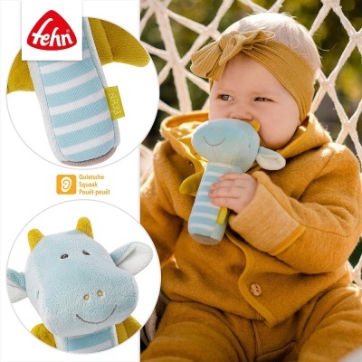 Bébé segurando brinquedo de pelúcia vaca azul claro com riscas