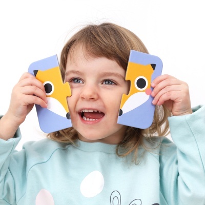 Criança segura peças de puzzle com desenho de raposa.