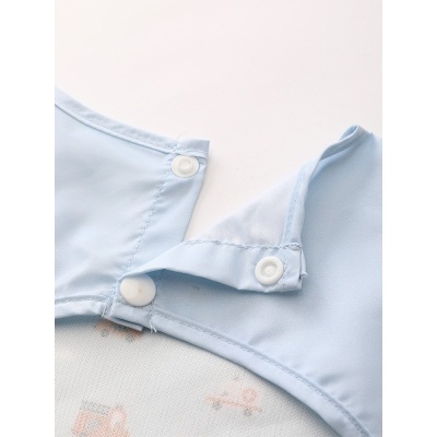 Peça de vestuário azul claro com botões de pressão brancos e padrão laranja subtil