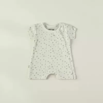 Macacão curto branco com padrão de flores pequenas e botões de pressão para bebé
