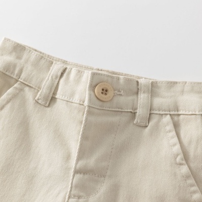 Calças bege claras com bolsos frontais e botão