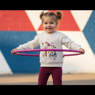 Criança a brincar com hula hoop cor-de-rosa junto a muro colorido