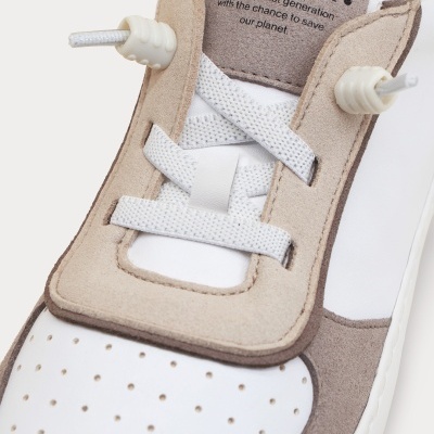 Sapatilha branca com detalhes em camurça bege e cinzento, atacadores brancos e texto no visor