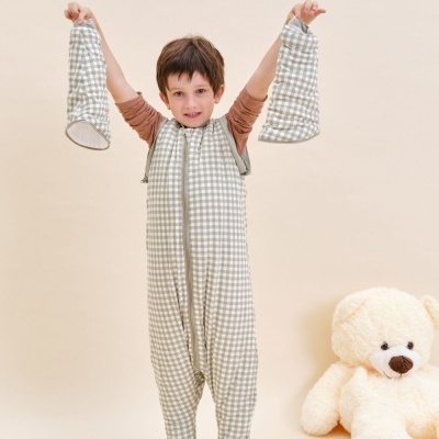 Criança com pijama xadrez cinza e branco e urso de peluche beige no chão