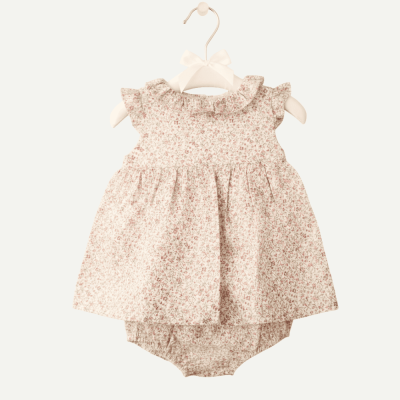 Conjunto de bebé com vestido floral branco e rosa e tapa-fraldas pendurado num cabide branco