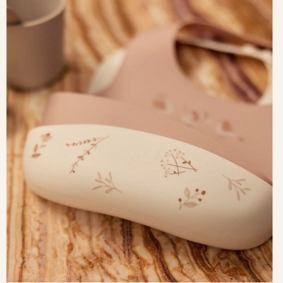 Colher de silicone com base branca e desenhos de ramos castanhos sobre superfície marmoreada.