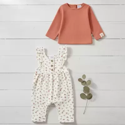Conjunto de roupa de bebé com camisola de malha laranja e macacão branco com padrão floral