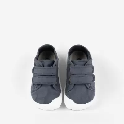 Sapatilhas infantis cinzentas com sola branca e fecho de velcro duplo.