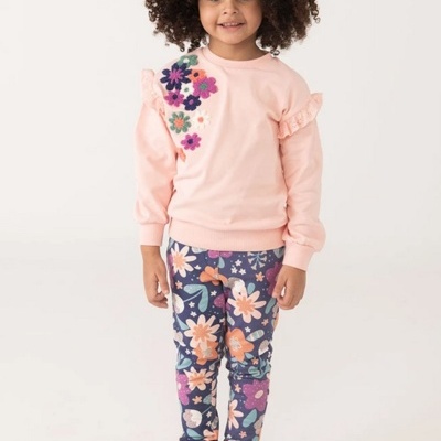 Criança com camisola rosa clara com flores bordadas e calças florais coloridas