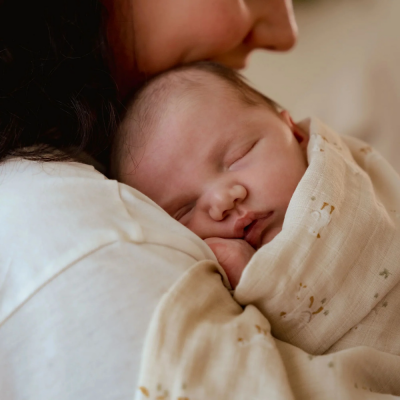 Bebé adormecido enrolado em cobertor bege claro com padrões florais