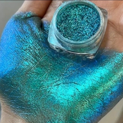 Pó brilho azul turquesa em frasco transparente e espalhado na mão