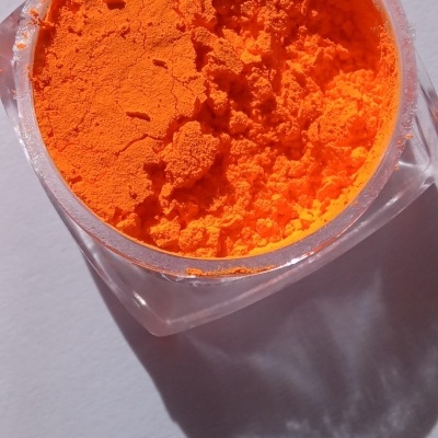 Recipiente com pigmento em pó laranja sobre superfície branca