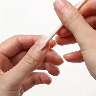 Mãos femininas a cuidar das unhas com pauzinho de madeira