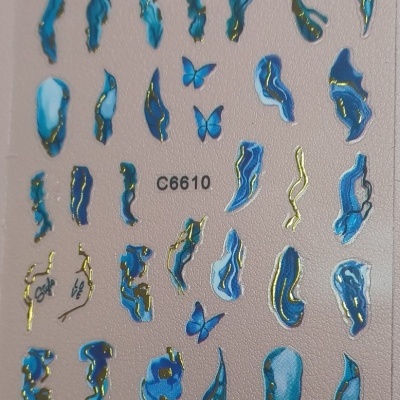 Adesivos de unhas azuis e dourados com borboletas e símbolos de amor num fundo salmão.