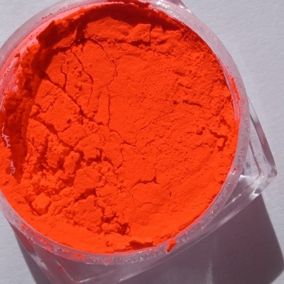 Pó pigmento laranja num recipiente plástico transparente sobre superfície branca