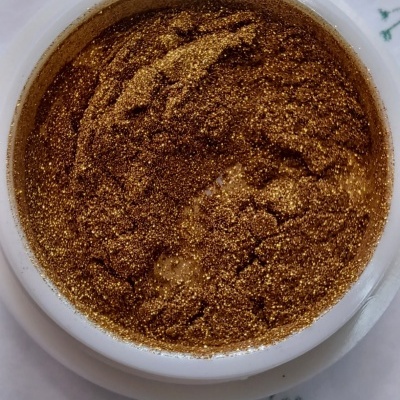 Pote branco com glitter dourado brilhante visto de cima sobre fundo branco com desenhos verdes