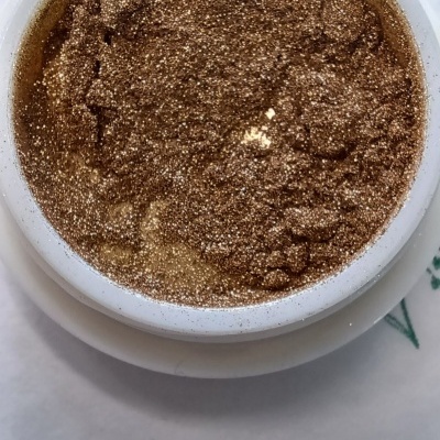 Pó dourado metálico em recipiente branco redondo