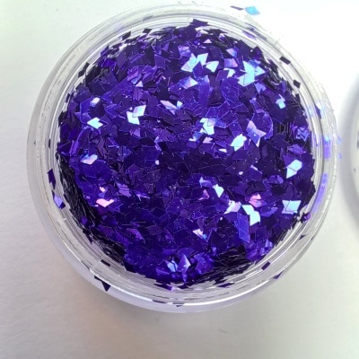 Frasco com glitter roxo metálico em pedaços pequenos sobre fundo branco