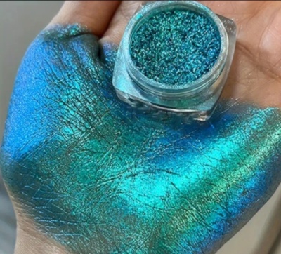 Pó brilho azul turquesa em frasco transparente e espalhado na mão