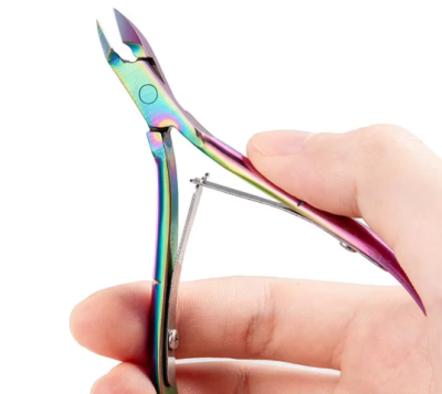 Alicate de cutículas metálico iridescente numa mão
