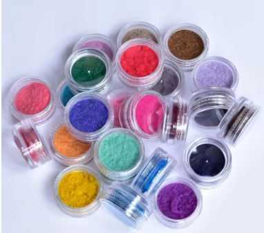 Pequenos recipientes transparentes com pós coloridos variados sobre fundo branco