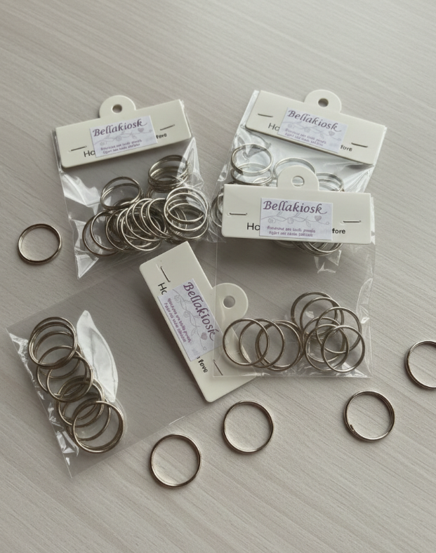 Anéis metálicos prateados em pacotes transparentes com etiquetas da marca Bellakiosk