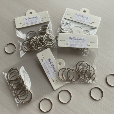 Anéis metálicos prateados em pacotes transparentes com etiquetas da marca Bellakiosk