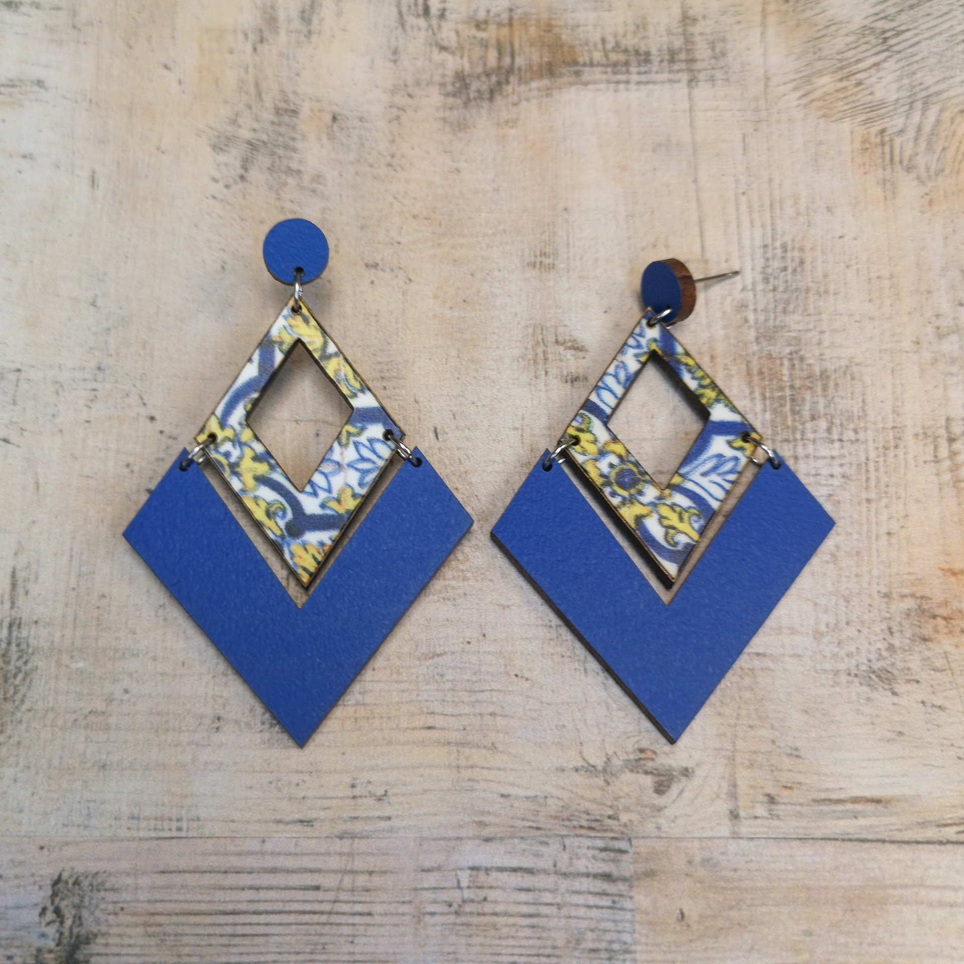 Brincos Caldas da Rainha Brincos geométricos em azul e padrão floral sobre superfície de madeira clara