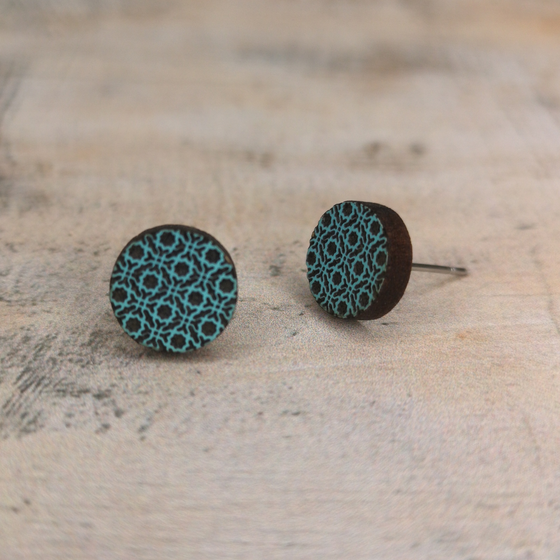 Brincos Alhambra I Brincos redondos de madeira com padrão azul turquesa num fundo preto.