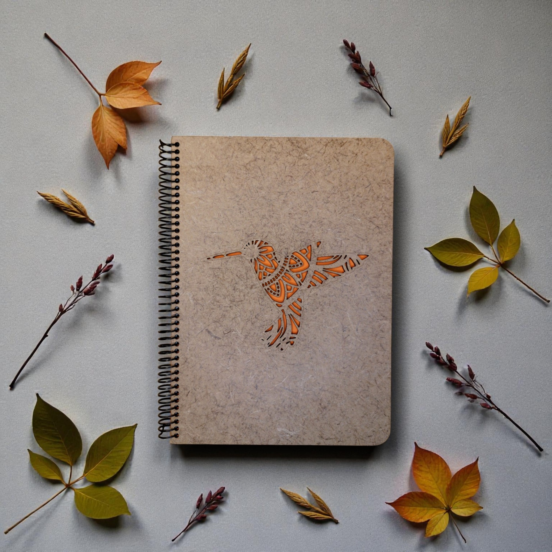 Caderno Beija-flor Caderno castanho com recorte de pássaro e folhas secas ao redor