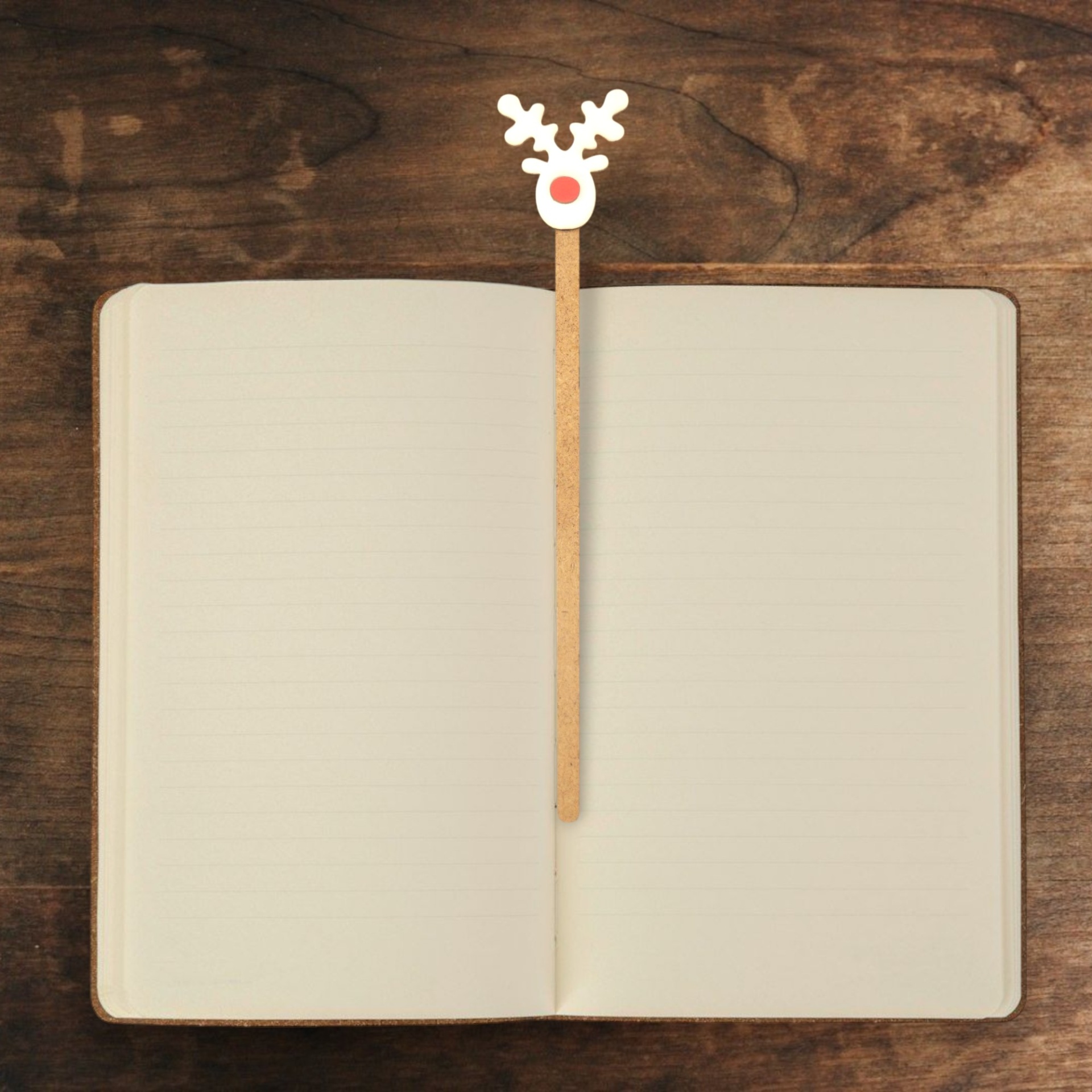 Marcador Rena de Natal Caderno aberto com marcador de rena sobre mesa de madeira