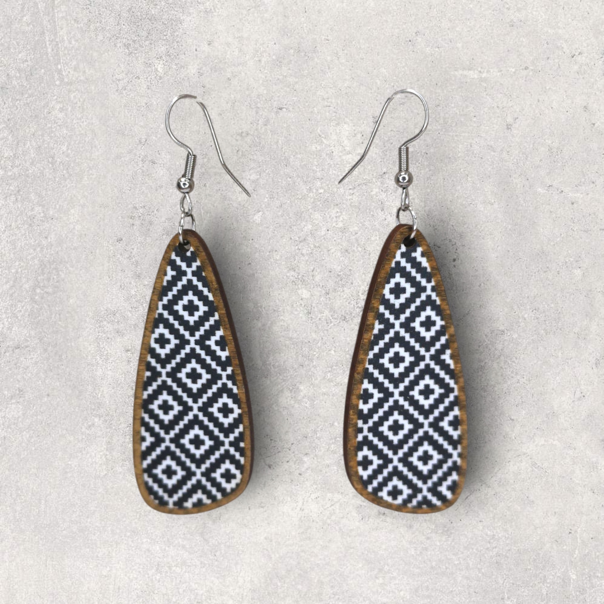Brincos Longos Brincos de madeira com padrão geométrico preto e branco no fundo cinza