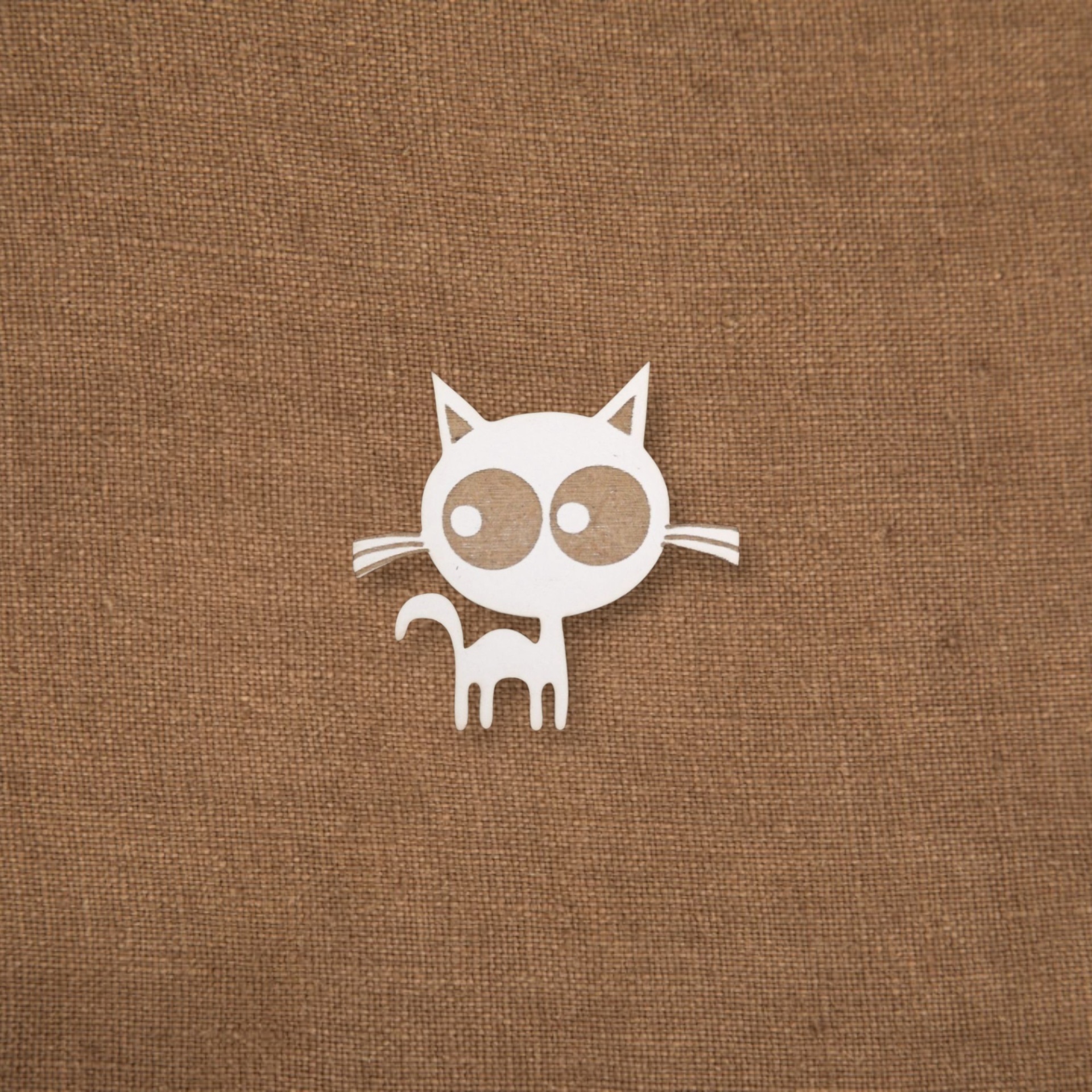 Pregadeira Sr. Gato Figura branca de gato estilizado sobre tecido castanho
