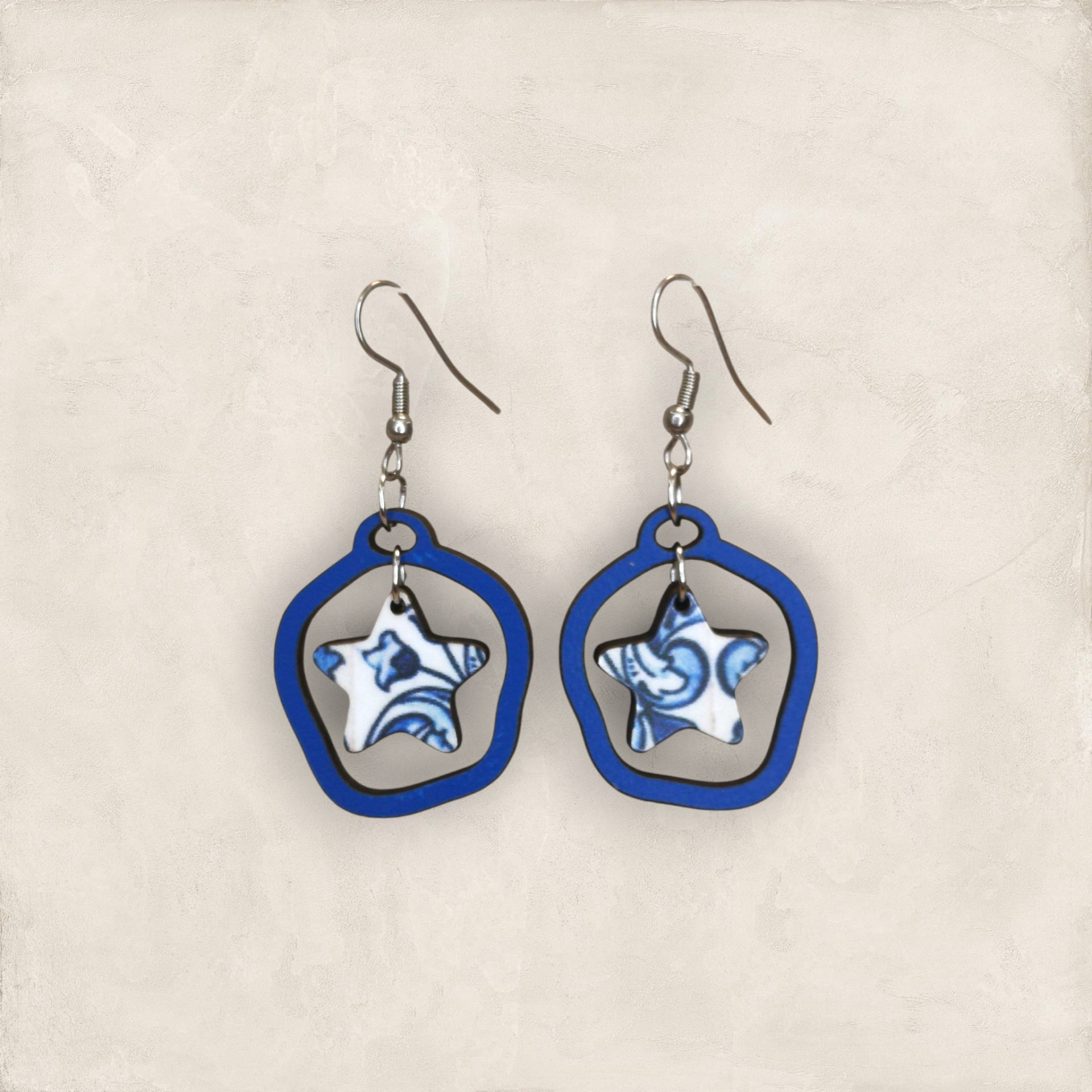 Brincos Estrela Brincos estrela azul e branco com estrutura azul em fundo bege