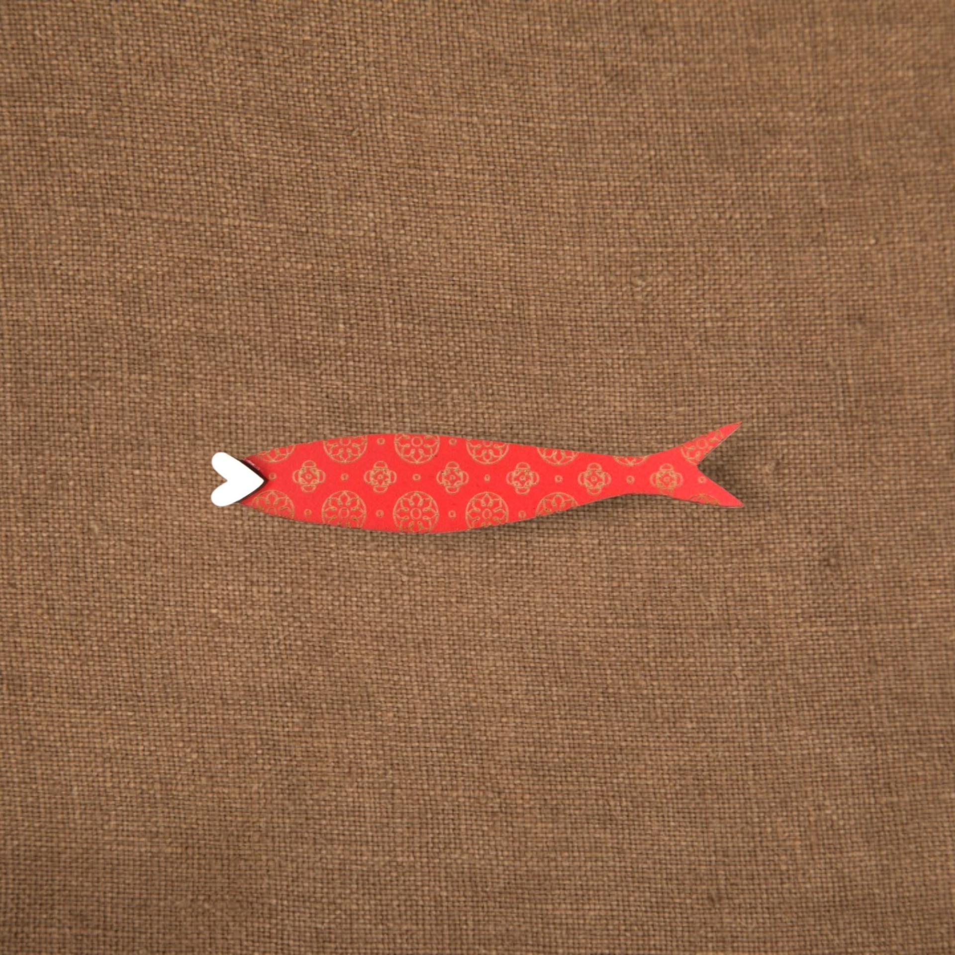 Pregadeira Sardinha Sardinha decorativa vermelha com padrões dourados e boca branca em fundo castanho