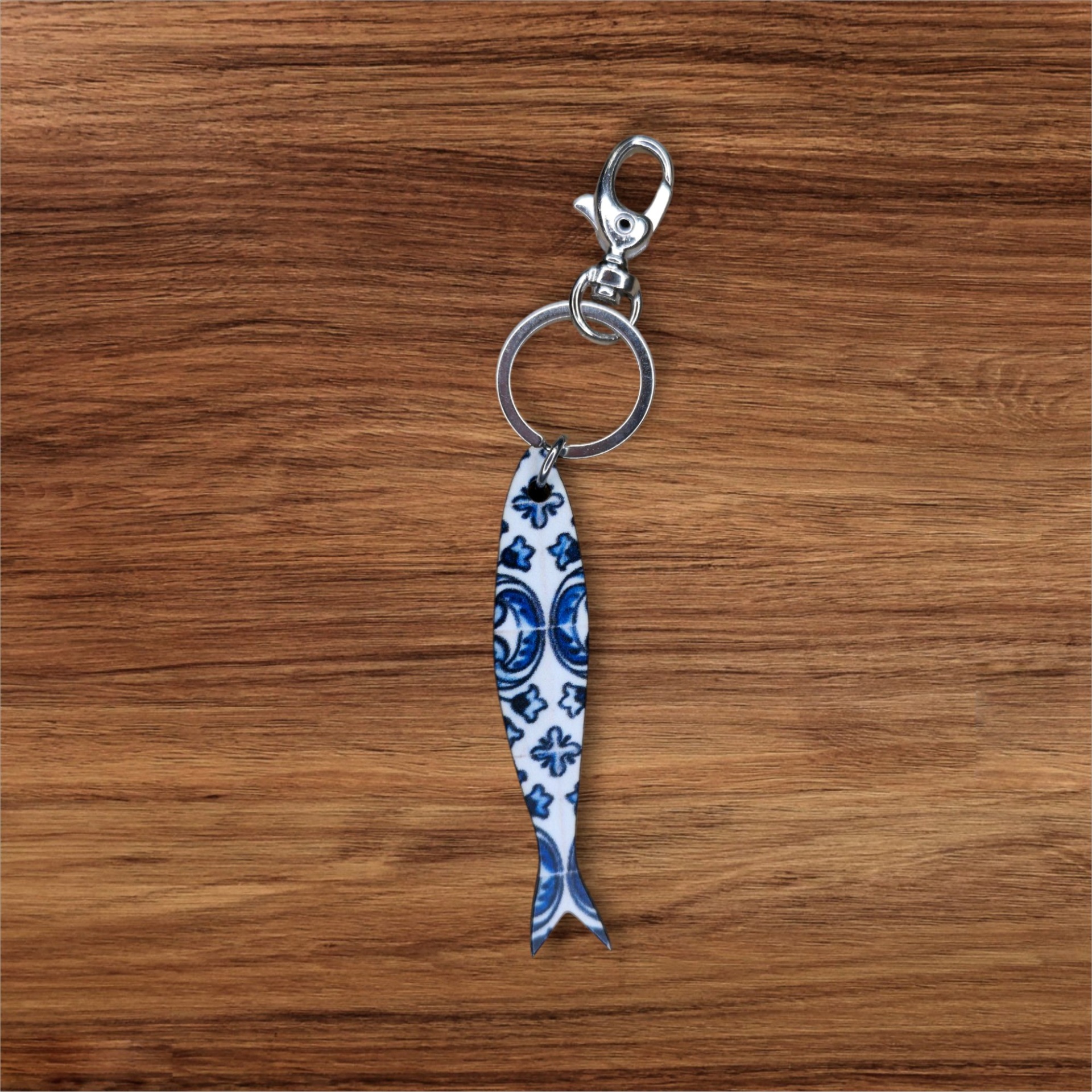 Porta-chaves Sardinha Azulejo Porta-chaves com pendente em forma de peixe azul e branco sobre madeira
